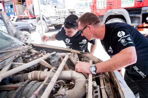 Autoserviso darbuotojų komanda remontuoja automobilį