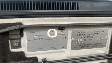Gamintojo lipduko pavyzdys ant Ford automobilio durelių staktos, kuriame aiškiai matomas spalvos kodas.
