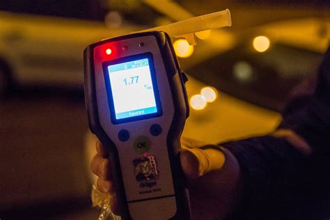 Nuotrauka su policijos automobiliu ir alkotesteriu