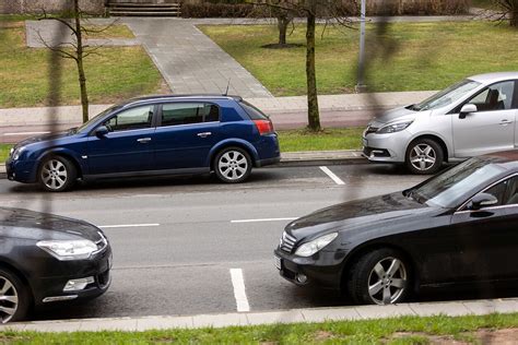 du žmonės, kalbantys prie automobilio, galbūt diskutuojantys apie KET pažeidimą