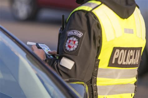 Jaunas žmogus, sėdintis prie automobilio vairo ir šypsantis. Egzamino simbolis.