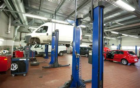 Teminis automobilio serviso vaizdas, kuriame meistrai dirba su automobiliais