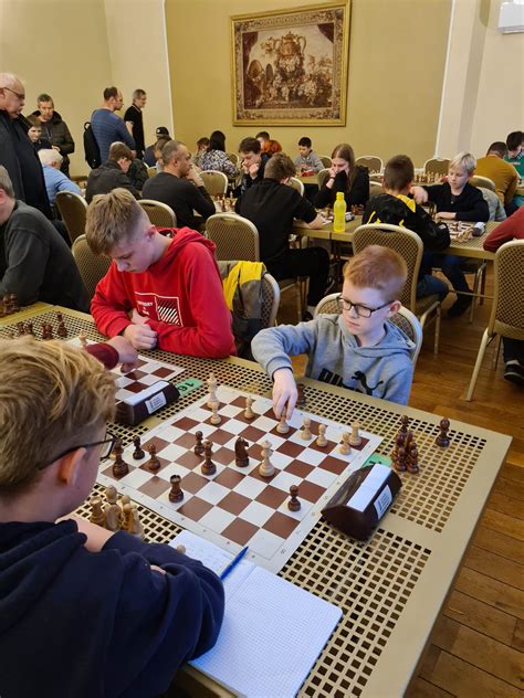 šachmatų mokytojas aiškina taisykles vaikui prie lentos