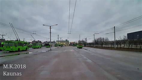 Tušti Kauno gatvės po lietingos nakties - troleibusų parkas fone
