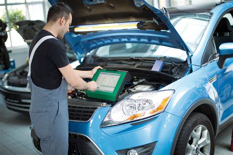 Automechanikas atliekantis diagnostiką su kompiuterine įranga automobilyje