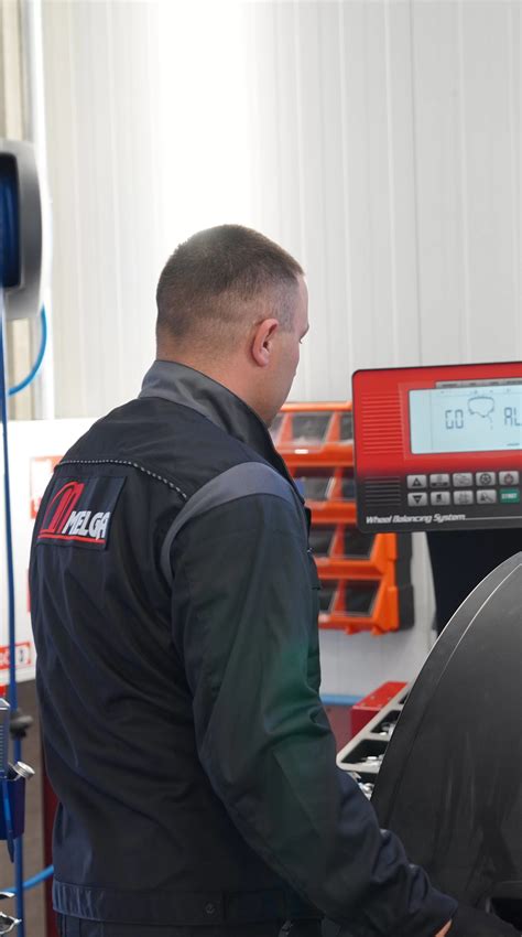 Ratų montavimas ir balansavimas autoservise, mechanikas dirba su įranga